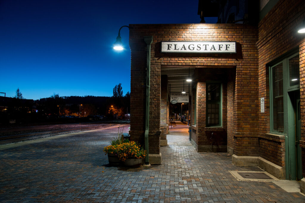 The historic Flagstaff train depot lit up at dusk along Route 66